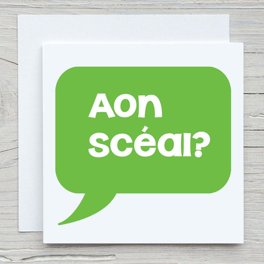 Irish greeting card and envelope with words Aon scéal? written in a speech bubble.  Translates to Any News?